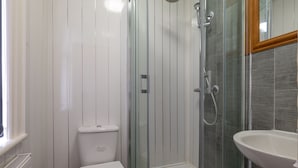A bathroom with a glass-enclosed shower, a white toilet, and a sink.