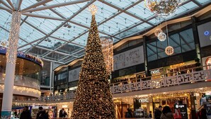 A large indoor shopping mall with a prominent Christmas tree and various stores.