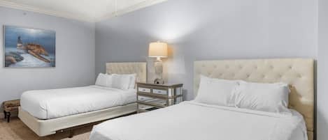 A hotel room with two beds, a ceiling fan, a nightstand with drawers, a lamp, and a painting of a sea turtle.
