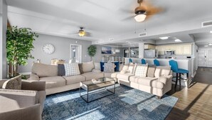 A modern living room with a sectional sofa, a glass coffee table, and a blue patterned rug. - Luxurious 5BR Oceanfront Condo at 4-Diamond North Beach Resort & Villas! (North Myrtle Beach)