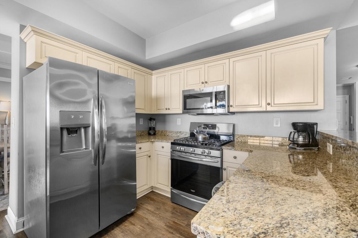 A kitchen with a stainless steel refrigerator, a microwave, a stove, and a coffee maker.
