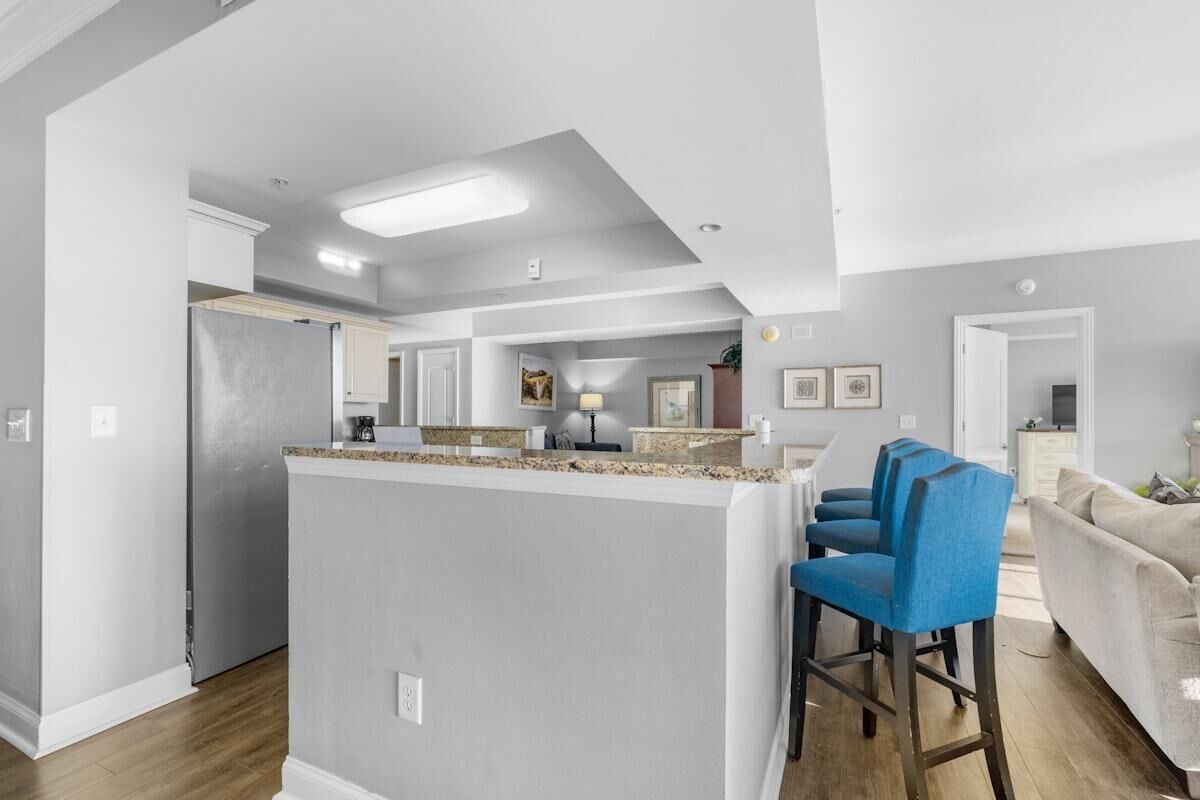 Una cocina moderna con una isla central, taburetes de bar y un área de comedor con sofá.