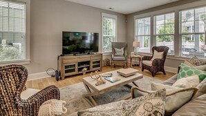 A living room with a television, two armchairs, a sofa, a coffee table, and a lamp.