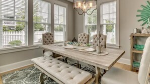A dining area with a wooden table, four upholstered chairs, a bench, and a chandelier.