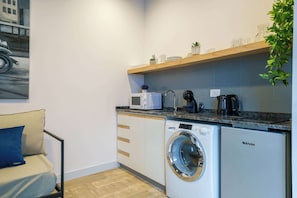 A compact kitchen with a washing machine, microwave, and coffee maker.