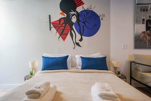 A hotel room with a bed, two blue pillows, a white bedspread, and towels on the bed.