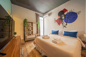 Une chambre d’hôtel équipée d’un lit, d’un bureau, d’étagères et d’un élément décoratif mural.