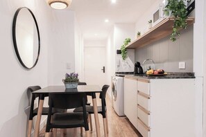 Una cocina compacta con comedor, lavadora y microondas en la encimera.