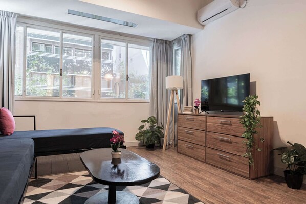 Una sala de estar moderna con un sofá, una mesa de centro, un televisor y un mueble de madera.