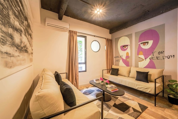Un salon moderne avec un canapé, une table basse et un mur décoré d’œuvres d’art.