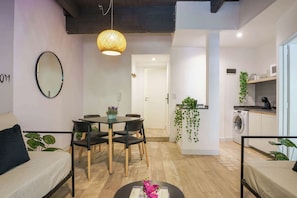 A modern living room with a dining area, a kitchen, and a laundry area.