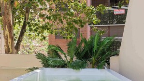 A rectangular pool with a clear water surface, surrounded by a low wall and a variety of green plants.