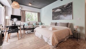 Une chambre avec un grand lit, un bureau avec des chaises, un canapé et un tableau au mur.