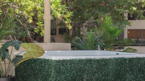 Un jardin sur le toit avec une piscine rectangulaire, entouré d’une végétation luxuriante et de grands arbres.