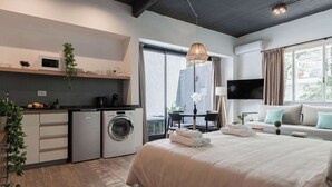 Une chambre d’hôtel moderne dotée d’un grand lit, d’un coin repas, d’une cuisine équipée d’un four à micro-ondes et d’un lave-linge.