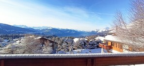 Eine verschneite Berglandschaft mit einer Holzhütte und einer Brücke im Hintergrund.