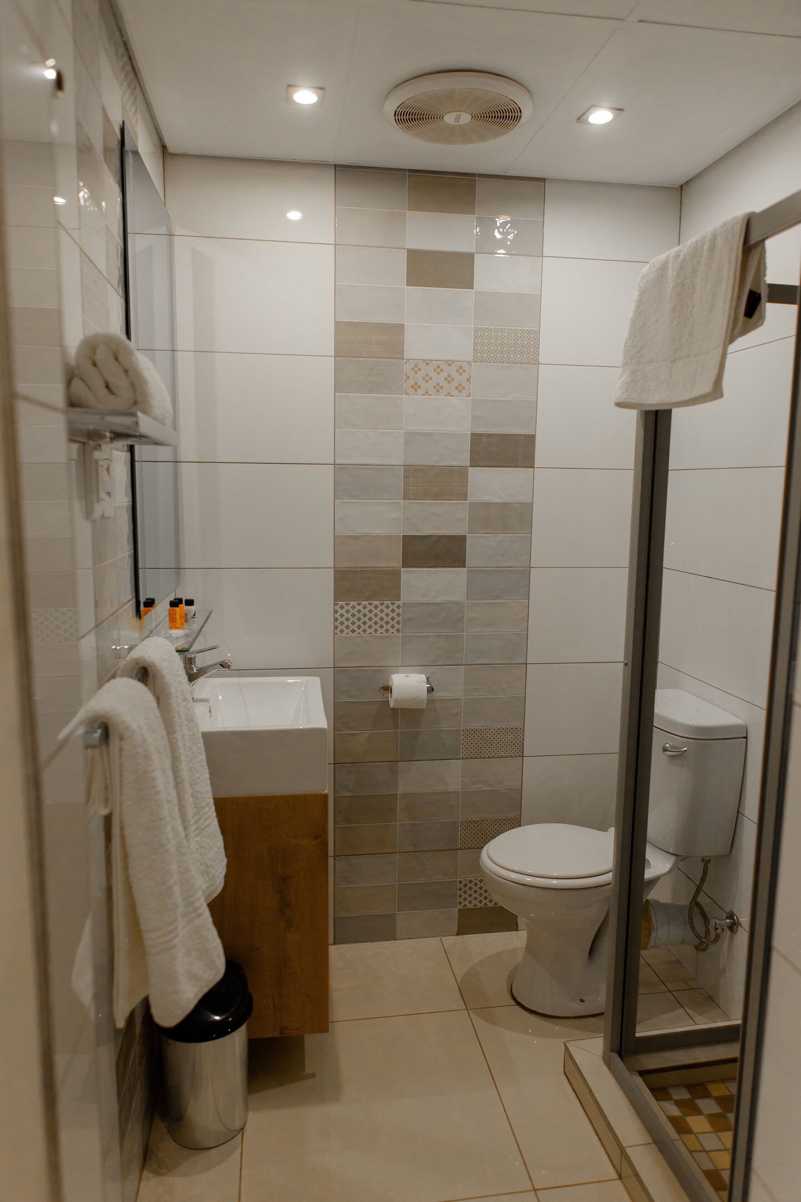 A modern bathroom with a glass shower enclosure, a wooden vanity, and a toilet.