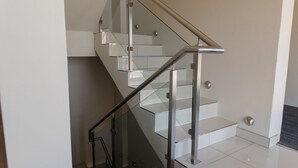 A modern staircase with glass railings and metal handrails. - Acres Inn Klerksdorp (Klerksdorp)
