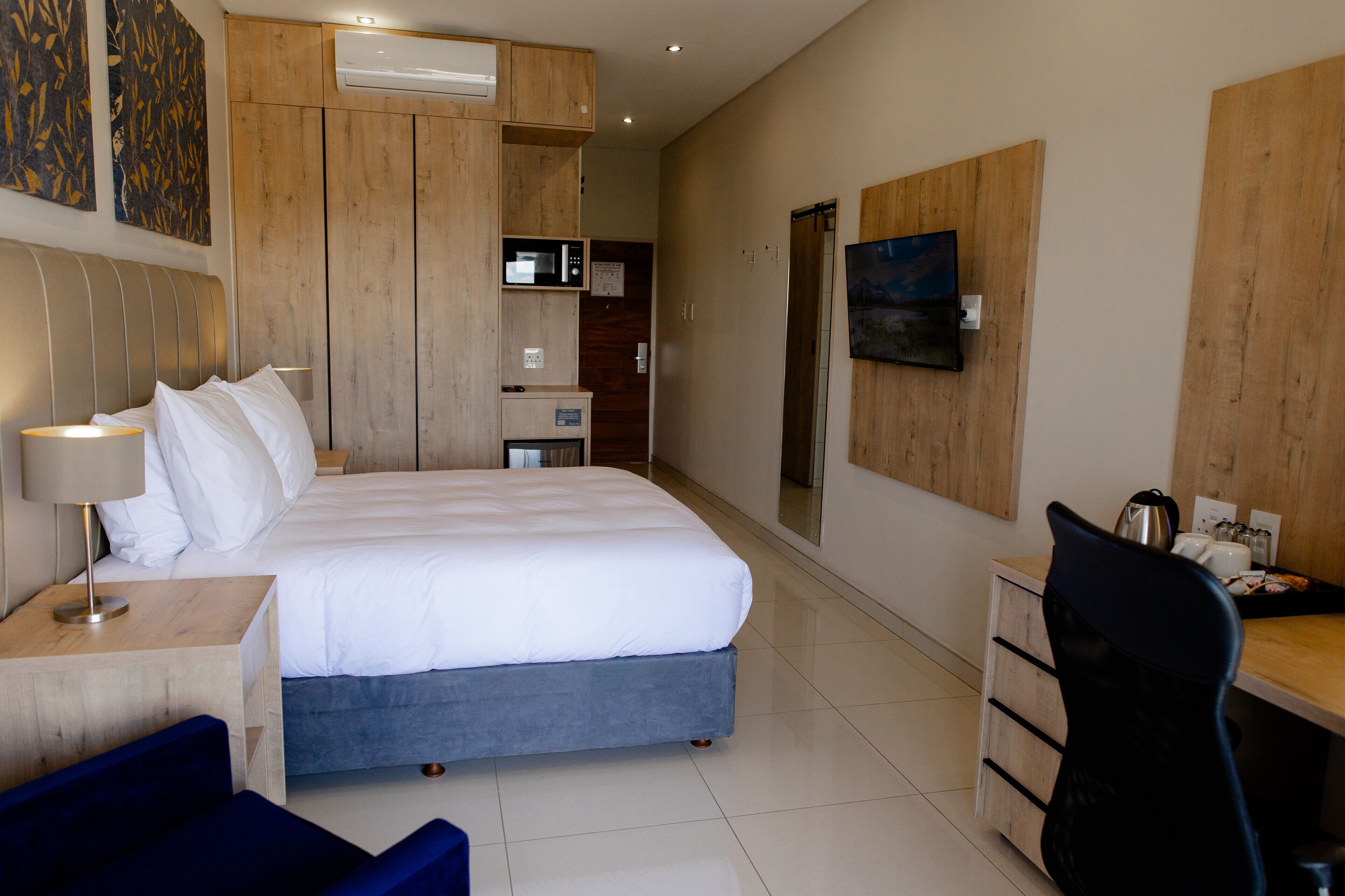Una habitación de hotel moderna con una cama grande, un escritorio, una silla y un armario.