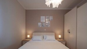 Une chambre à coucher avec un grand lit, deux tables de chevet avec des lampes, une armoire et des œuvres d’art murales.