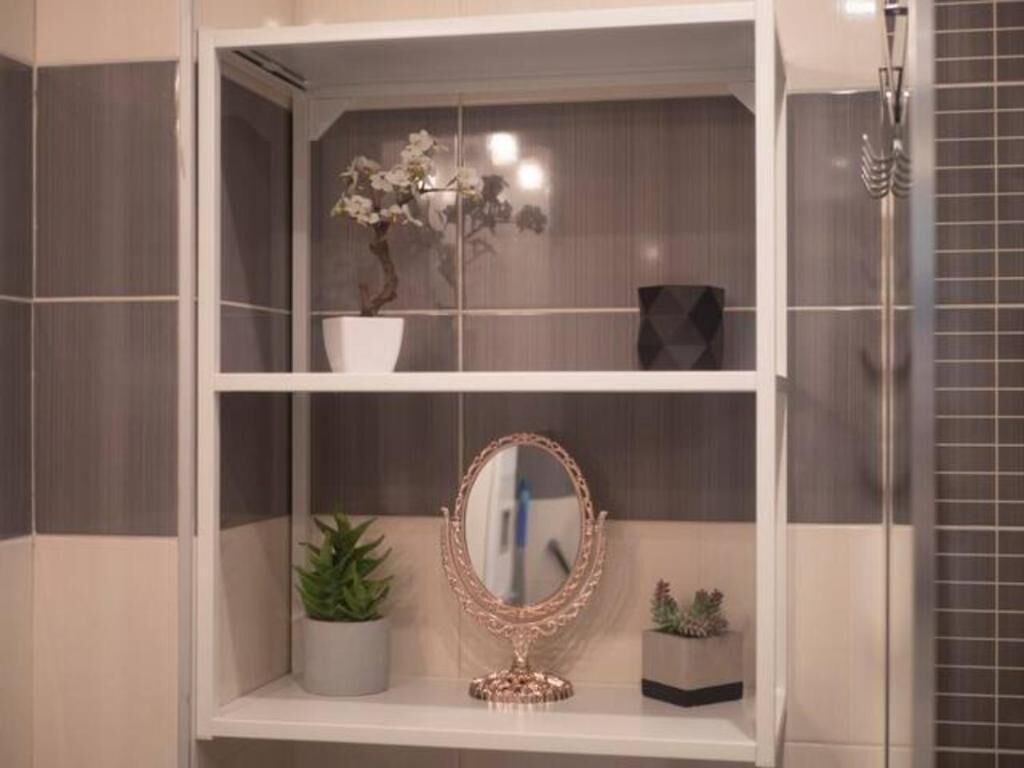 A bathroom vanity with a mirror, a potted plant, and a vase with flowers.