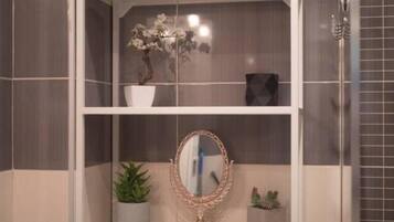 A bathroom vanity with a mirror, a potted plant, and a vase with flowers.