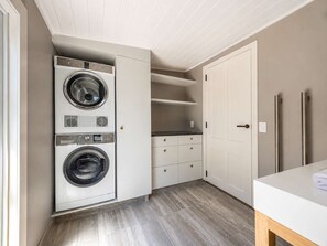 A laundry room with two stacked washers and dryers, a white door, and a countertop with a towel.
