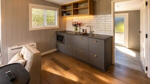 Una cocina moderna con horno empotrado, un lavamanos y un estante de madera sobre la encimera.