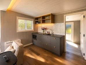 Een moderne keuken met een inbouwoven, een spoelbak en een houten plank boven het aanrecht.