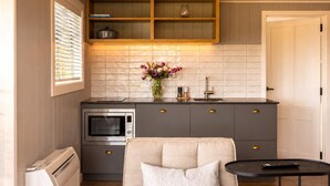 Una cocina compacta con horno empotrado, microondas y estante de madera sobre la encimera.