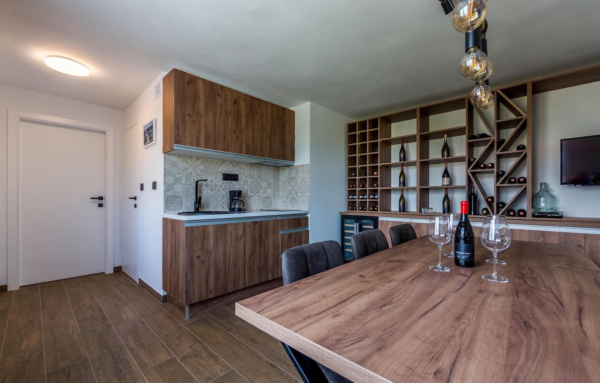 Une cuisine moderne avec des meubles en bois, un meuble-bar intégré et une table à manger avec des chaises.