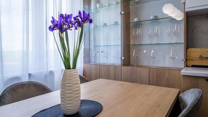 A dining area with a wooden table, a vase with purple flowers, and a glass display case with wine glasses. - Amazing home in Labin - Rabac (Labin - Rabac)