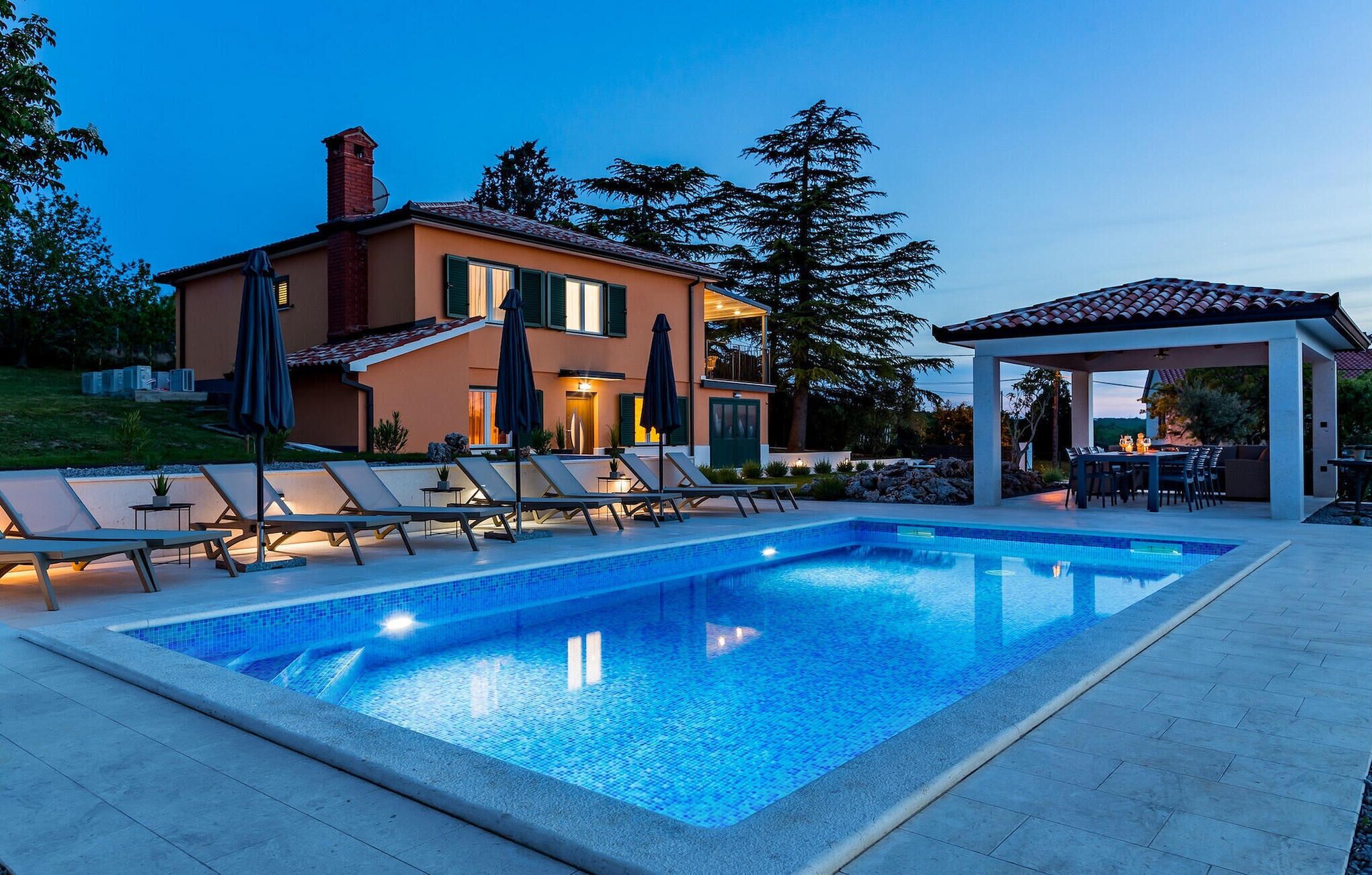 Une maison moderne dotée d’une piscine, d’un espace salon extérieur et d’un patio couvert.
