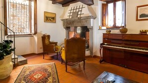 Una sala de estar acogedora con chimenea, un piano y una alfombra grande.