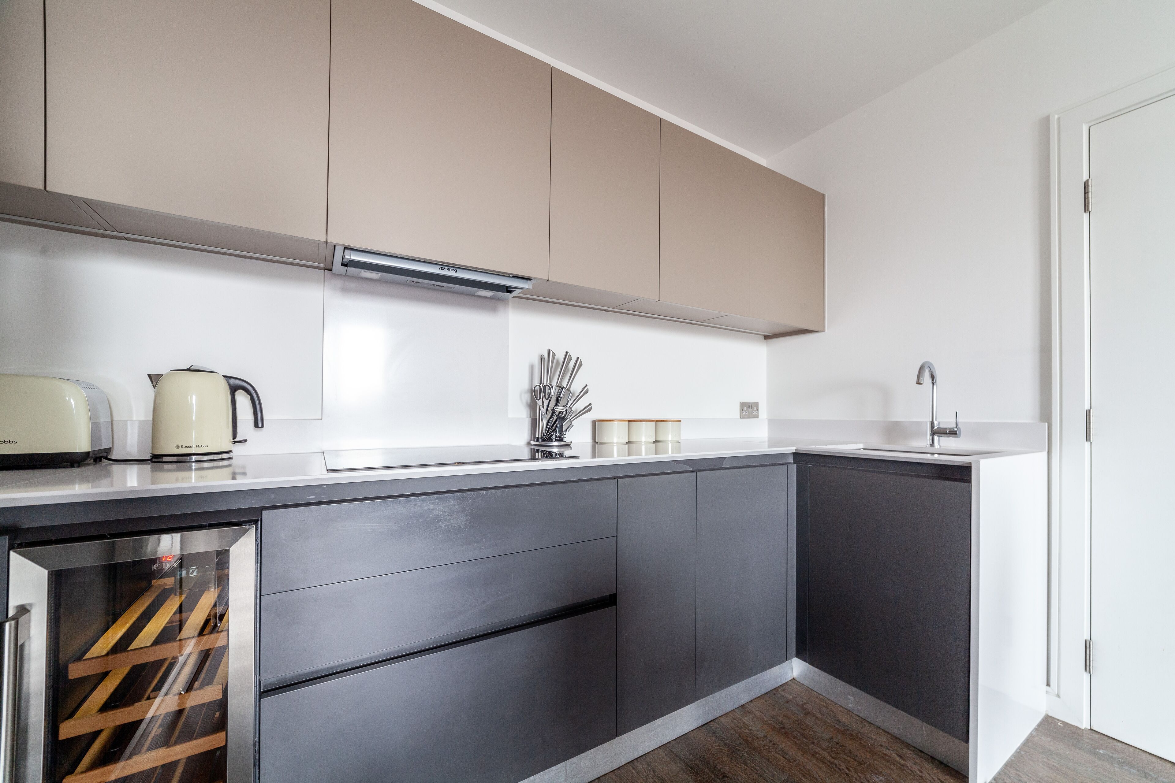 A modern kitchen with a built-in wine cooler, stainless steel appliances, and a minimalist design.