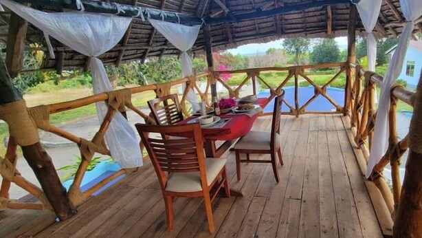 An outdoor wooden deck with a table and chairs, surrounded by a bamboo fence.