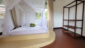 A bedroom with a bed under a canopy, a wooden shelf, and a view of greenery outside.