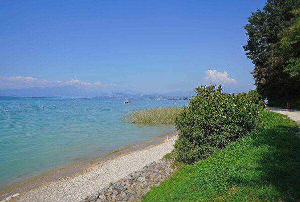 A pebble beach with clear water and distant mountains.