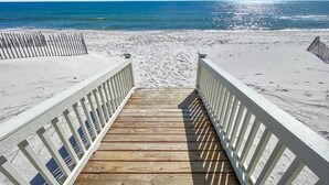 Une promenade en bois qui mène à une plage de sable et offre une vue sur l’océan.