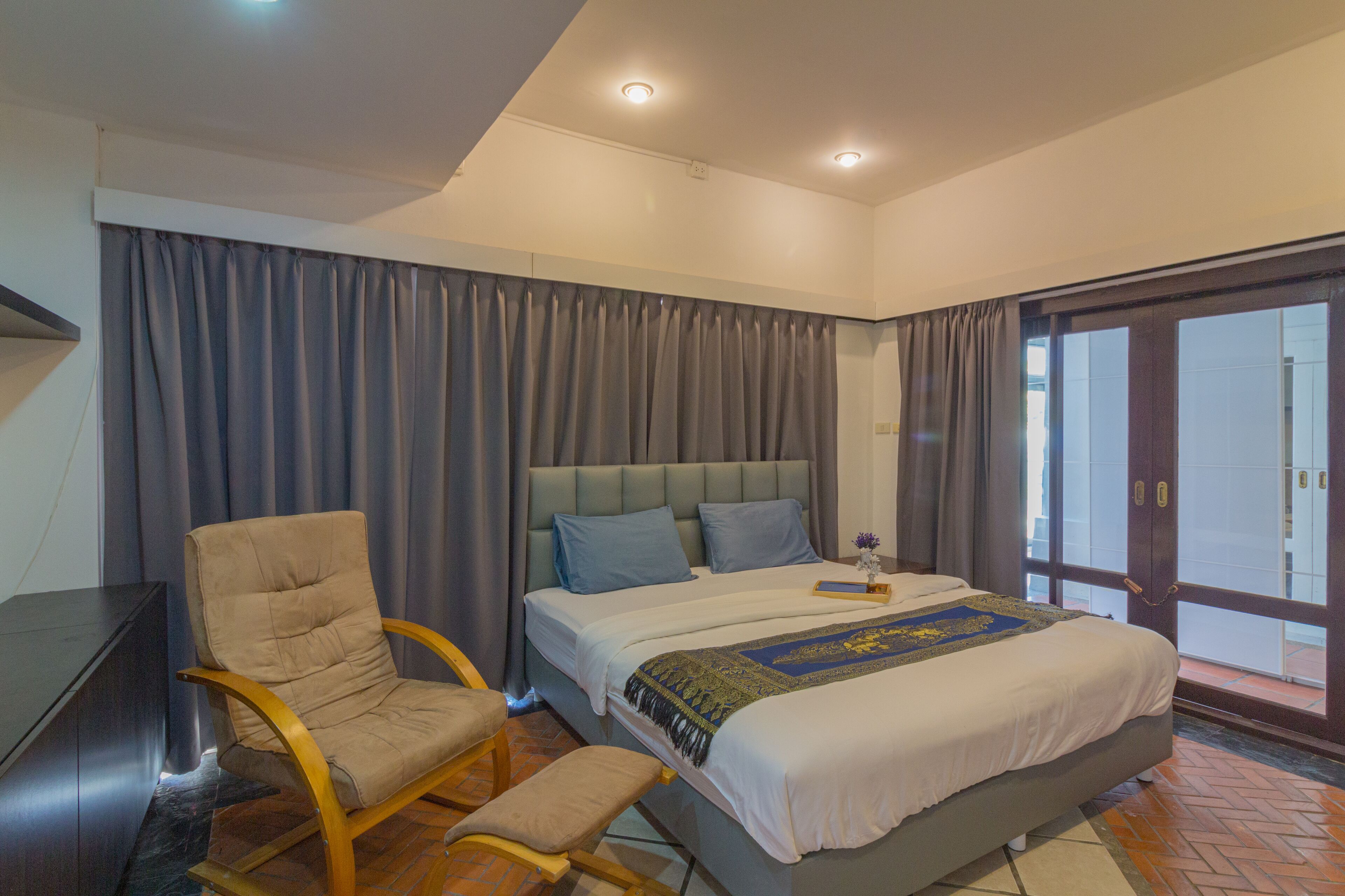 Ein Schlafzimmer mit Bett, Stuhl, Schreibtisch und Blick ins Freie.