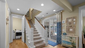 Un escalier menant à un deuxième étage, un espace buanderie et une console décorative au design inspiré du thème de la plage.