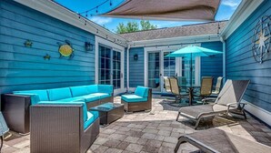 A covered patio with blue walls, wicker furniture, and a table with chairs.