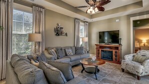 A living room with a sofa, armchairs, a coffee table, a fireplace, and a television.