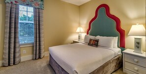 Une chambre à coucher avec un lit, une table de chevet, une lampe et des rideaux.