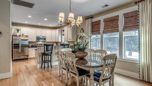 A modern kitchen with white cabinets, a stainless steel refrigerator, and a dining area with a round table and chairs. - A Spacious 3 Bdrm Oasis at North Beach Resort (North Myrtle Beach)