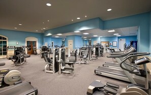 Ein Fitnessstudio mit unterschiedlichen Trainingsgeräten, darunter Laufbänder, Crosstrainer und Kraftgeräte.
