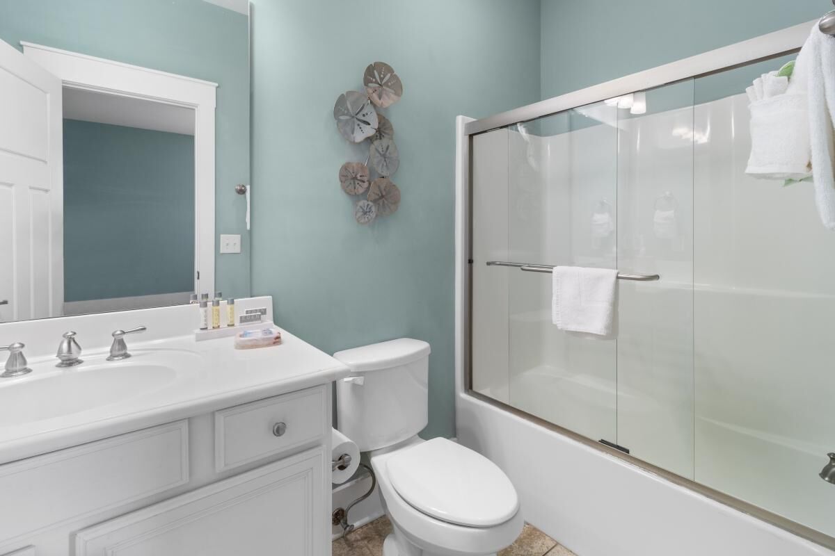 Un baño con lavamanos blanco, inodoro y ducha con mampara de vidrio.
