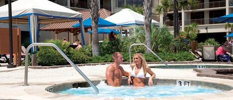 Zona de piscina con jacuzzi, palmeras y un edificio identificado como 'North Beach Towers' al fondo.