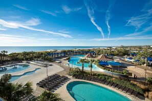 A resort with multiple swimming pools, lounge areas, and a view of the ocean.