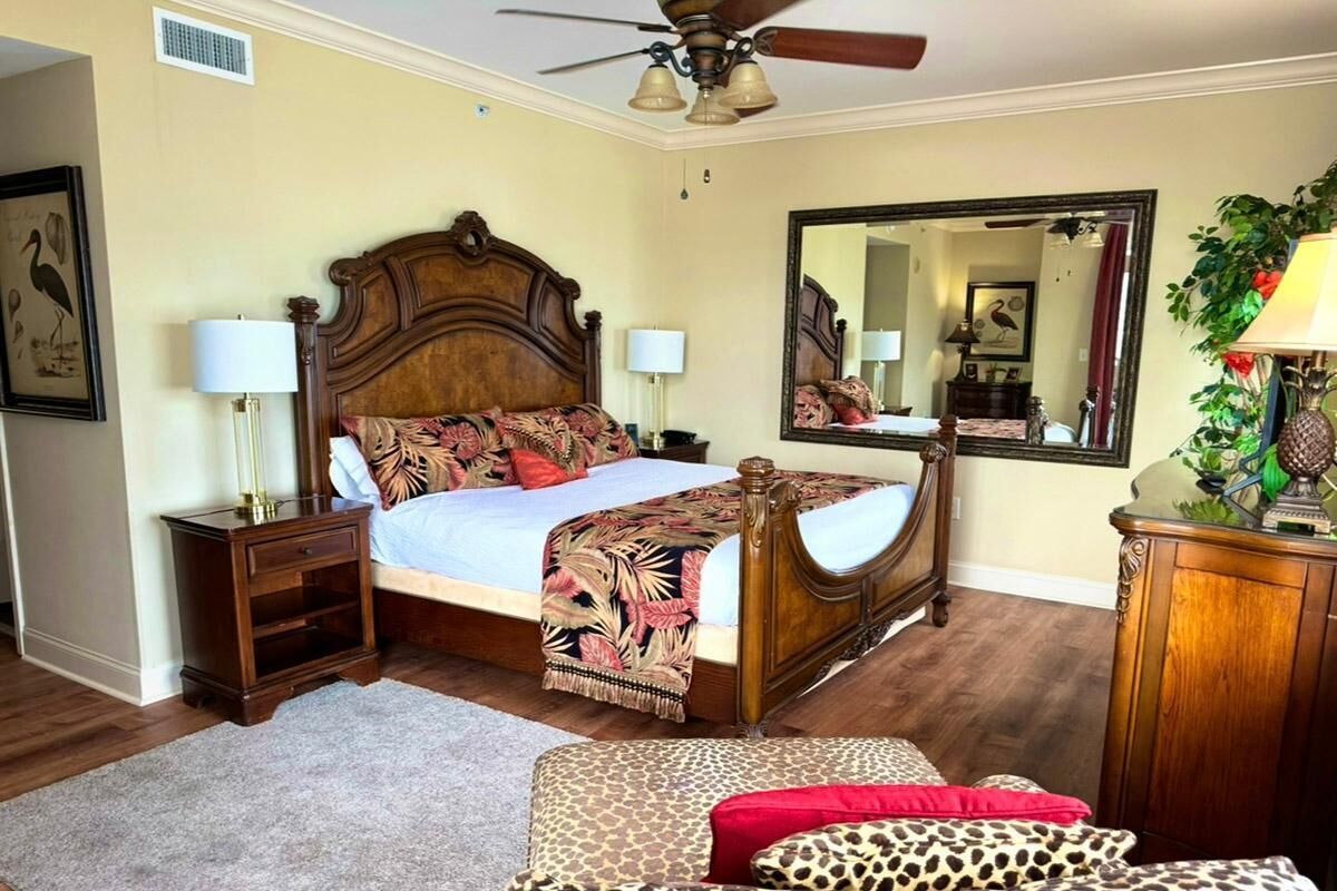 Un dormitorio con una cama de madera, mesitas de noche, un espejo y una planta decorativa.